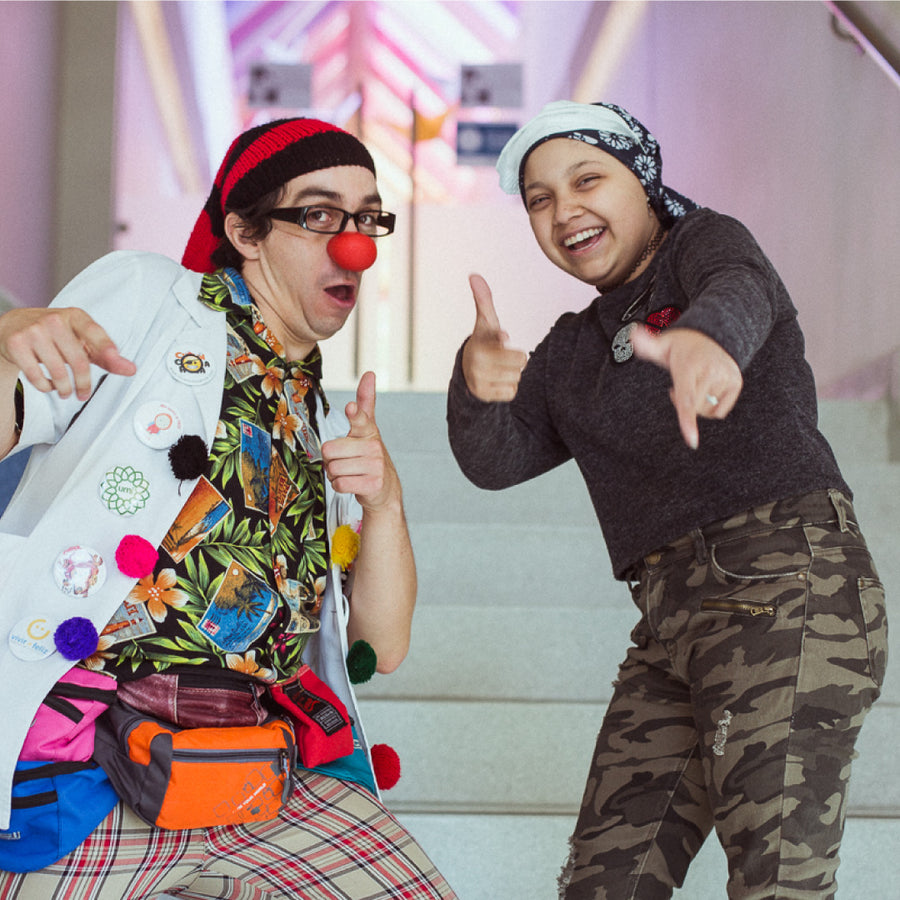 Un clown y una joven sonríen juntos durante una visita.