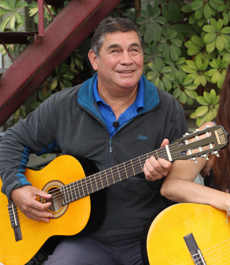 Luis sonríe mientras sostiene una guitarra.