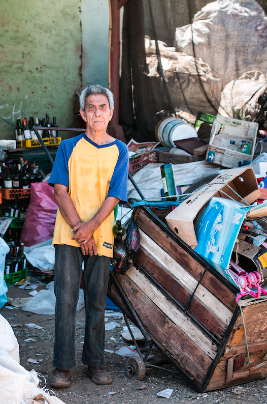 Una persona junto a cajas y herramientas de reciclaje.