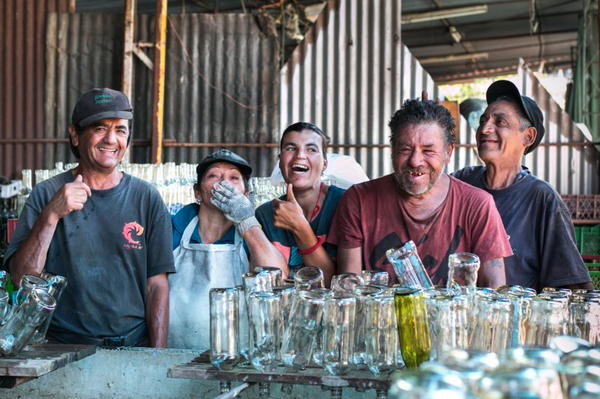 El equipo de recicladores y lavadores de botellas reunido junto a las botellas recuperadas.