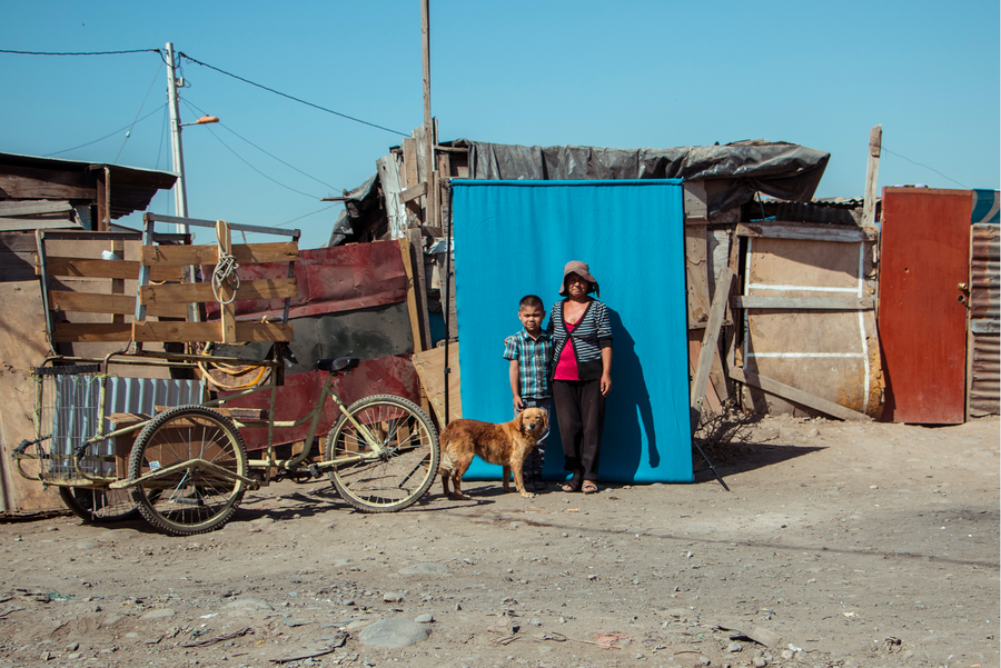 Dos personas junto a una casa y su carro recolector.
