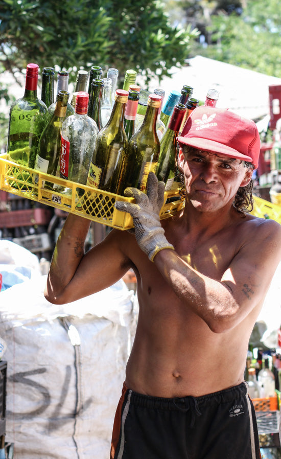 Una persona sostiene una caja de botellas recuperadas.